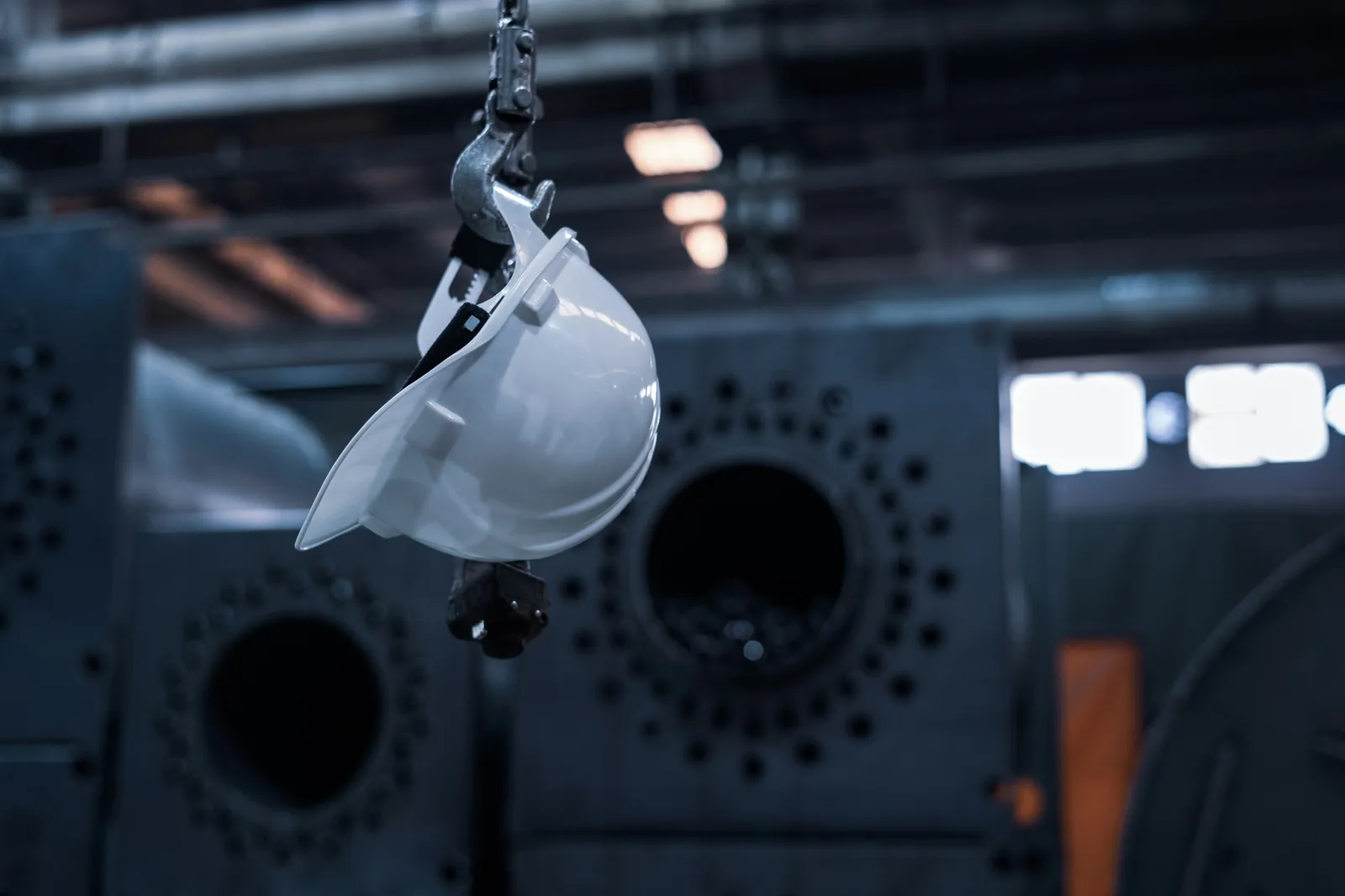 White safety hard hat hanging in an industrial plant